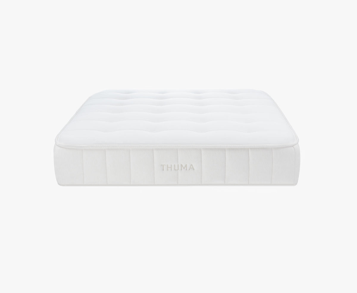 A white, rectangular Hybrid Mattress with a tufted surface and THUMA embroidered on the side, shown against a plain white background.