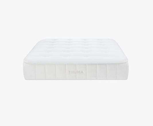 A white, rectangular Hybrid Mattress with a tufted surface and THUMA embroidered on the side, shown against a plain white background.