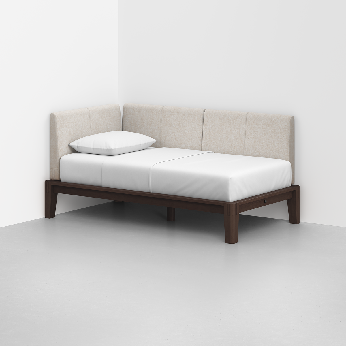 The Classic Daybed features a dark wooden frame, white mattress, single pillow, and beige upholstered backrest, set in the corner of a white room with a light gray floor.