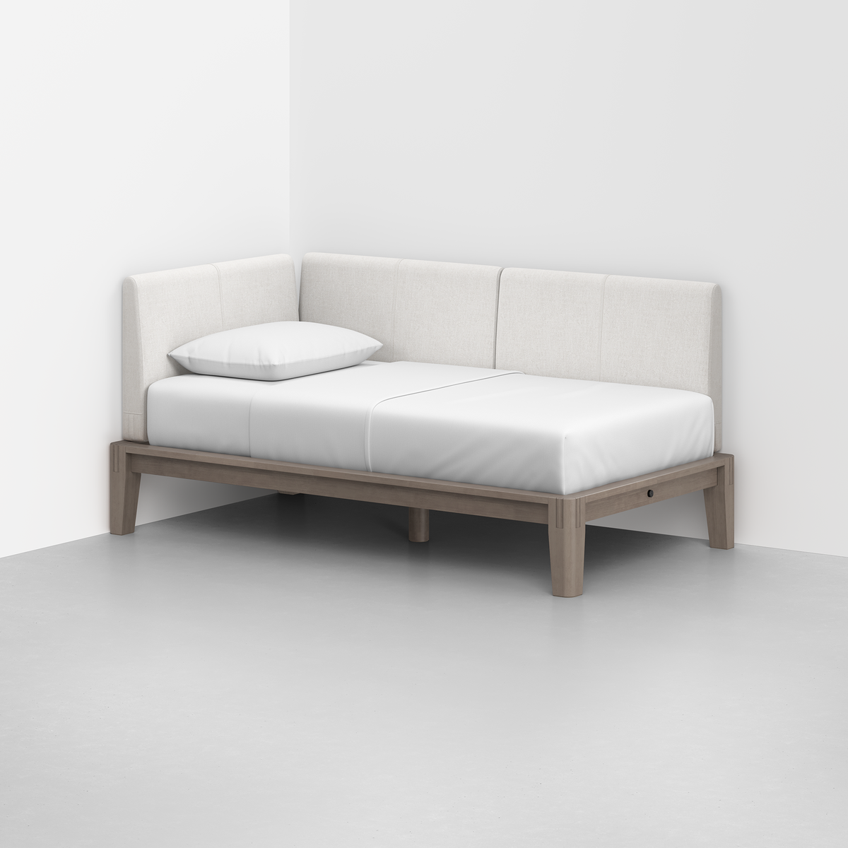 The Classic Daybed features a light wood frame, white mattress, single white pillow, and beige upholstered backrests, perfectly set against two white walls in a minimalist modern room.