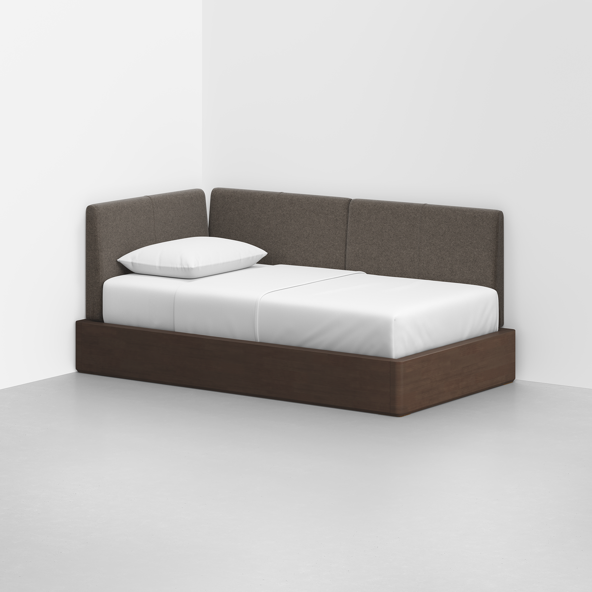 The Essential Daybed, featuring a dark wooden frame and brown upholstered backrest, is placed in the corner of a minimally decorated room and topped with crisp white sheets and a single pillow.