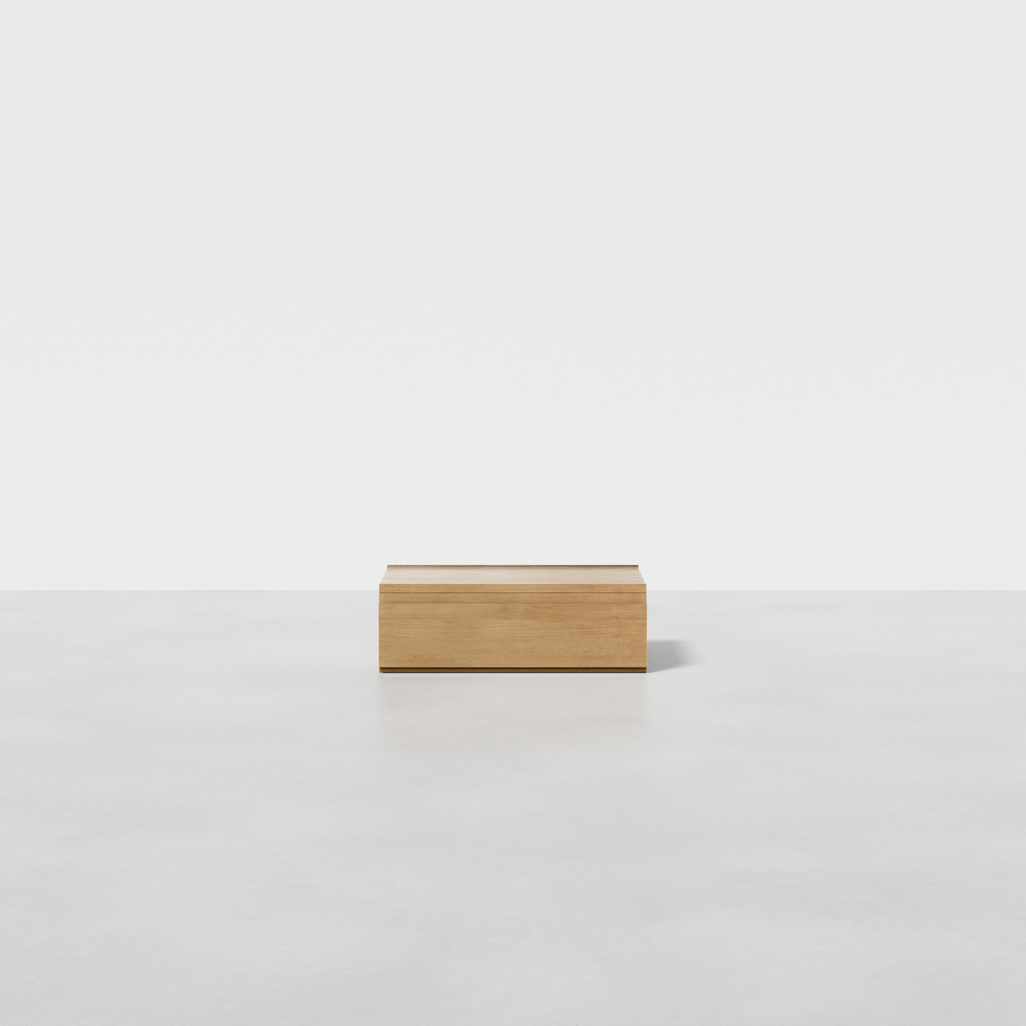 The Nest Nightstand Low, a small and light wooden box, sits centered on a smooth white surface with a white background.