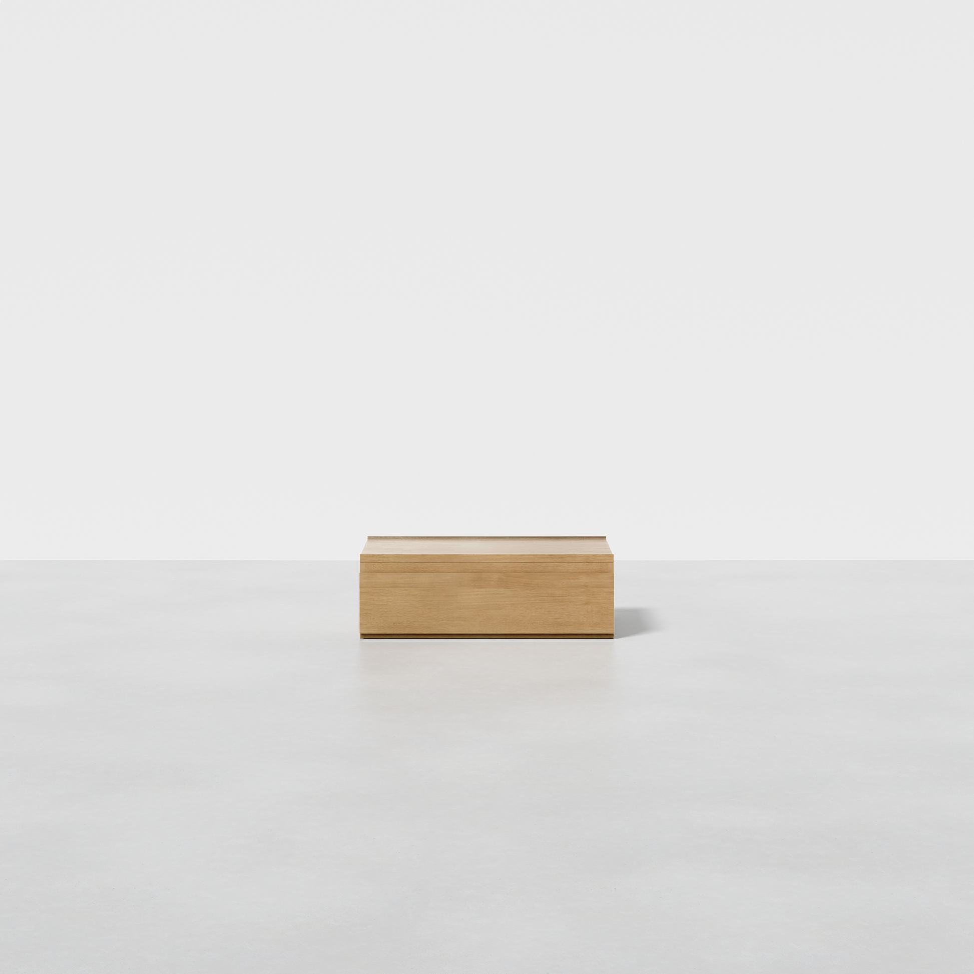 The Nest Nightstand Low, a small and light wooden box, sits centered on a smooth white surface with a white background.