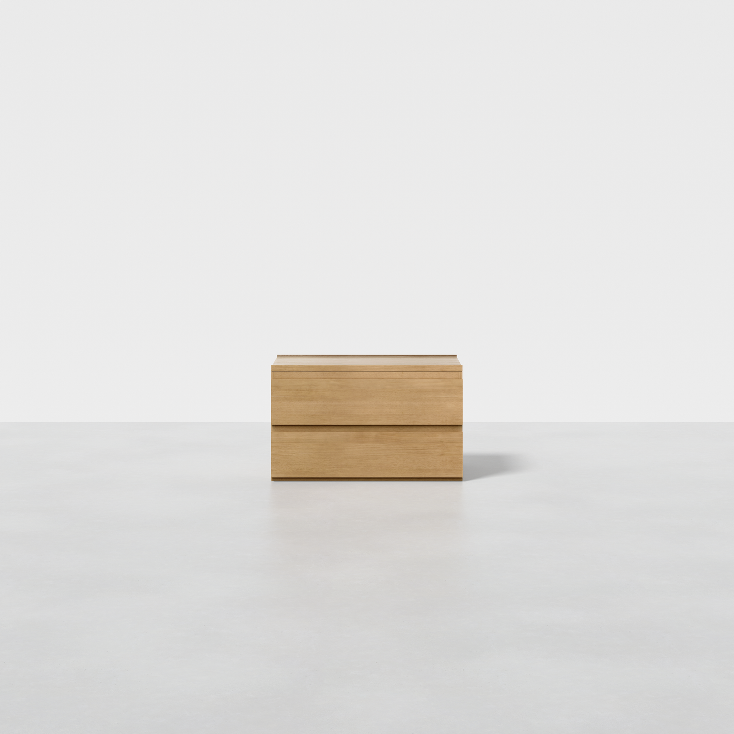 The Nest Nightstand, a small rectangular piece in light wood with clean lines, sits on a smooth light gray surface against a plain white background.