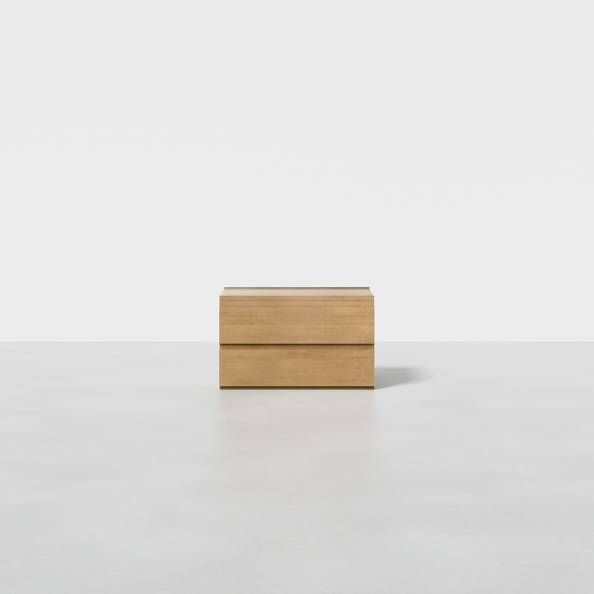 The Nest Nightstand, a small rectangular piece in light wood with clean lines, sits on a smooth light gray surface against a plain white background.