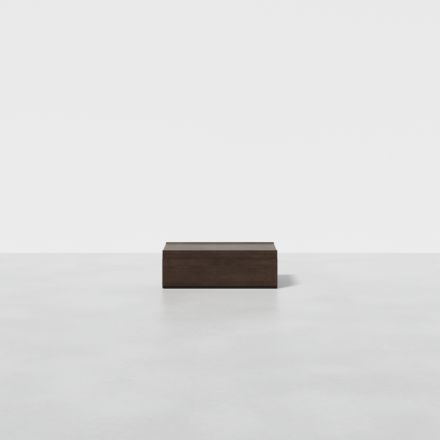 The Nest Nightstand Low, a simple dark brown rectangular wooden piece, rests on a smooth light gray surface with a plain white background.