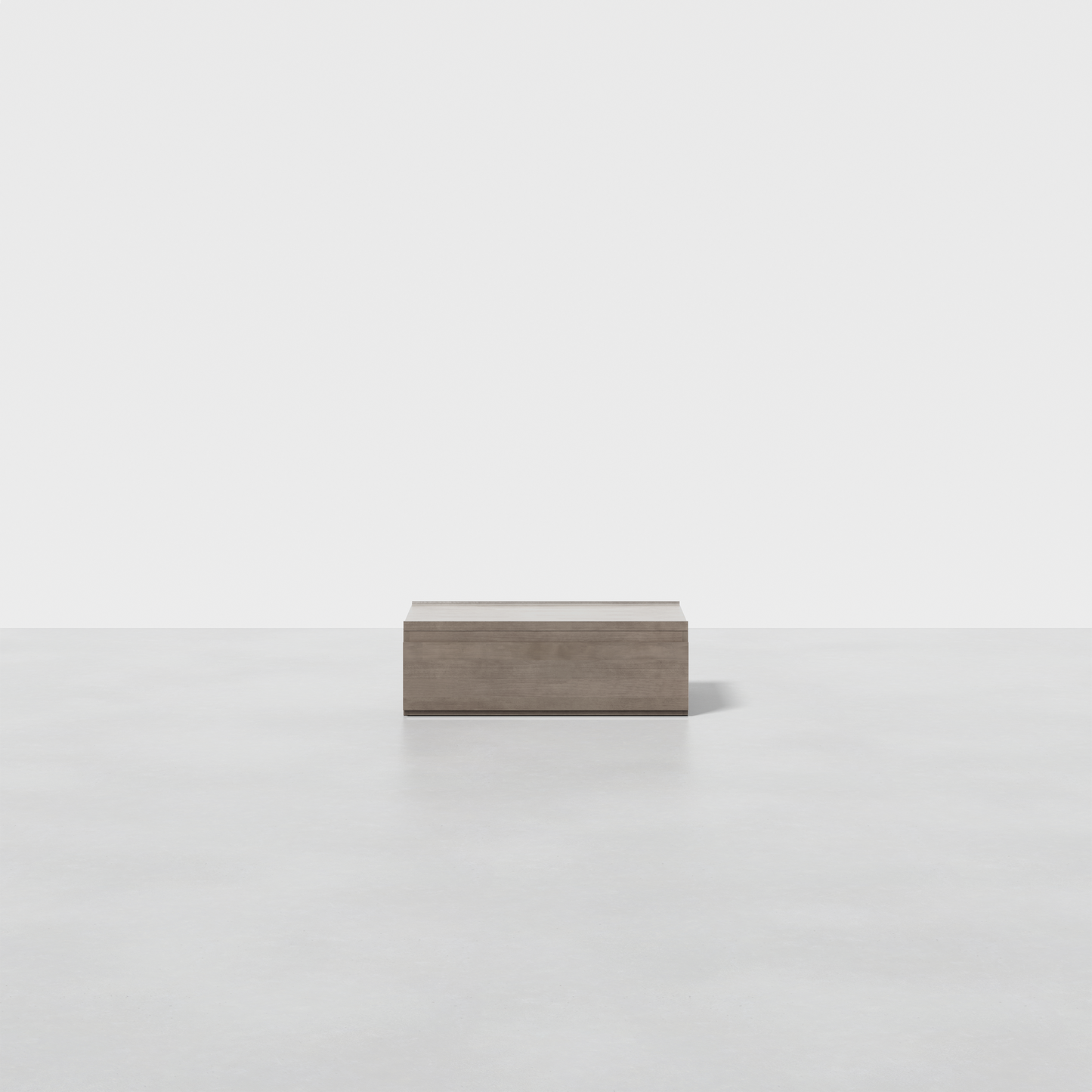 The Nest Nightstand Low, a minimalist rectangular wooden box, is placed on a smooth light gray floor with a plain white background.