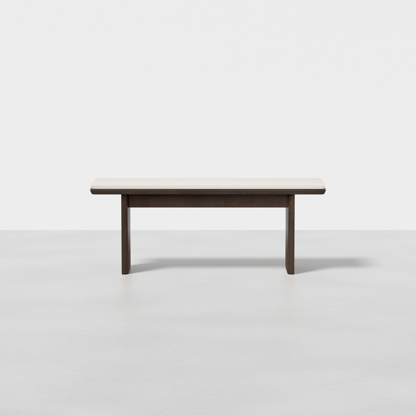 The Pillar Bench, featuring a minimalist design with a light wood seat and dark legs, is set against a plain white background on a light gray floor.