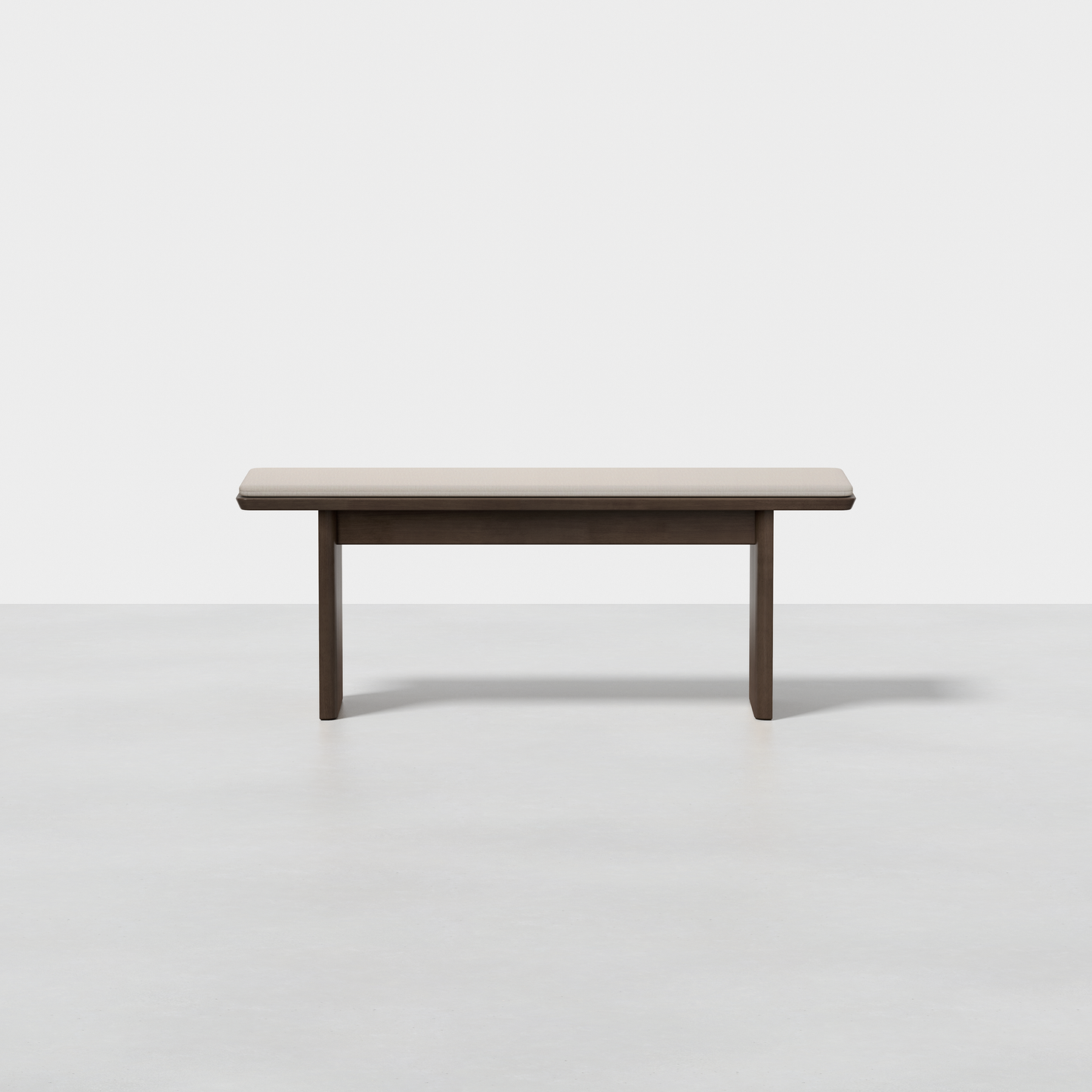 The Pillar Bench is a simple, modern wooden bench with a rectangular seat and straight legs, displayed on a smooth light gray floor against a plain white background.