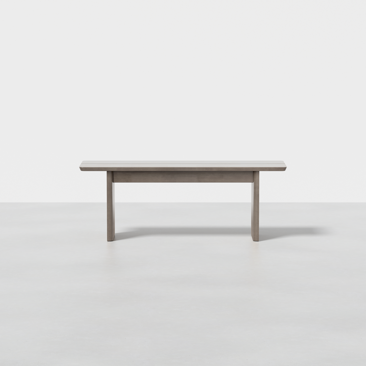 The Pillar Bench is a simple, modern wooden bench featuring a rectangular seat and straight legs, set on a seamless light grey floor with a plain white background.