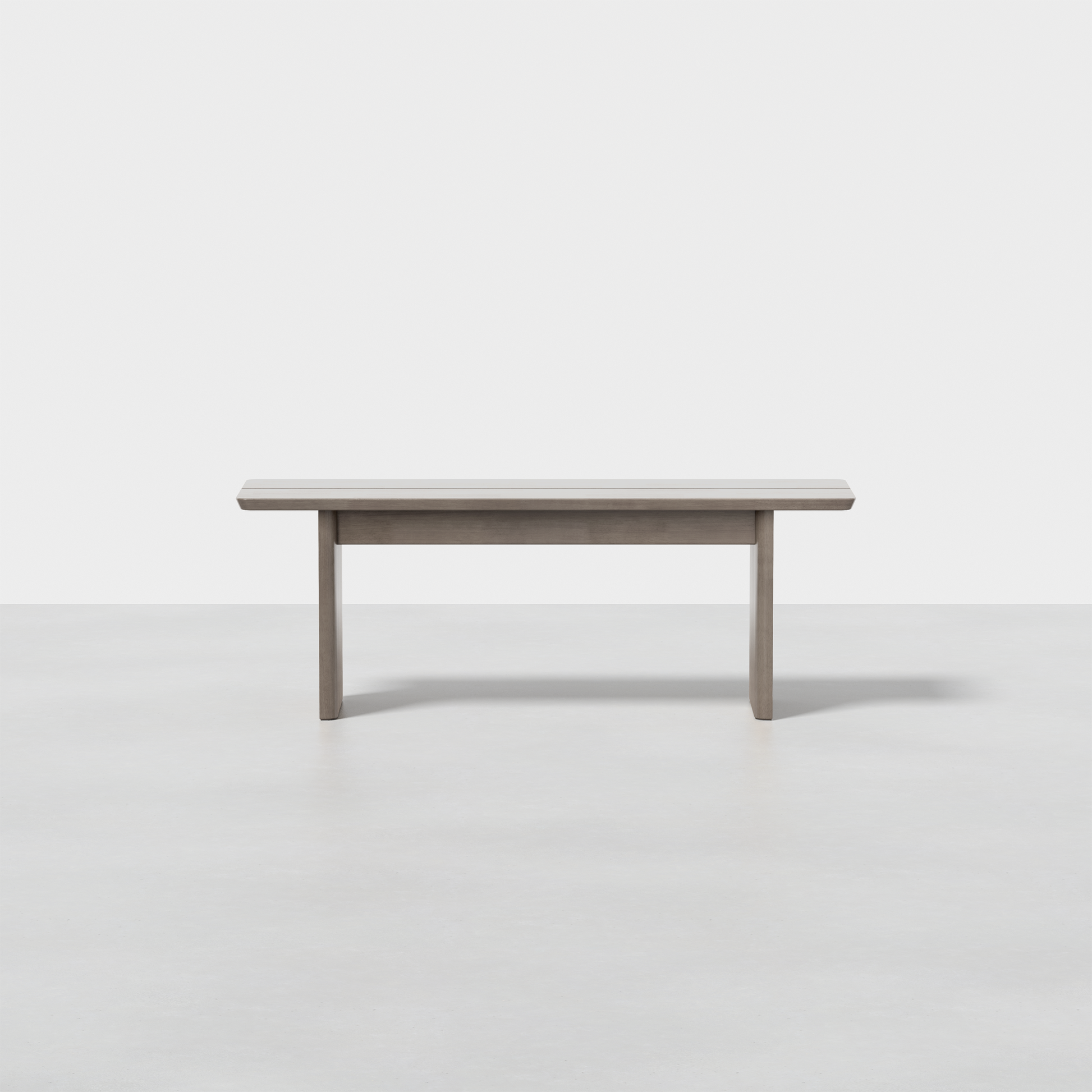 The Pillar Bench is a simple, modern wooden bench featuring a rectangular seat and straight legs, set on a seamless light grey floor with a plain white background.