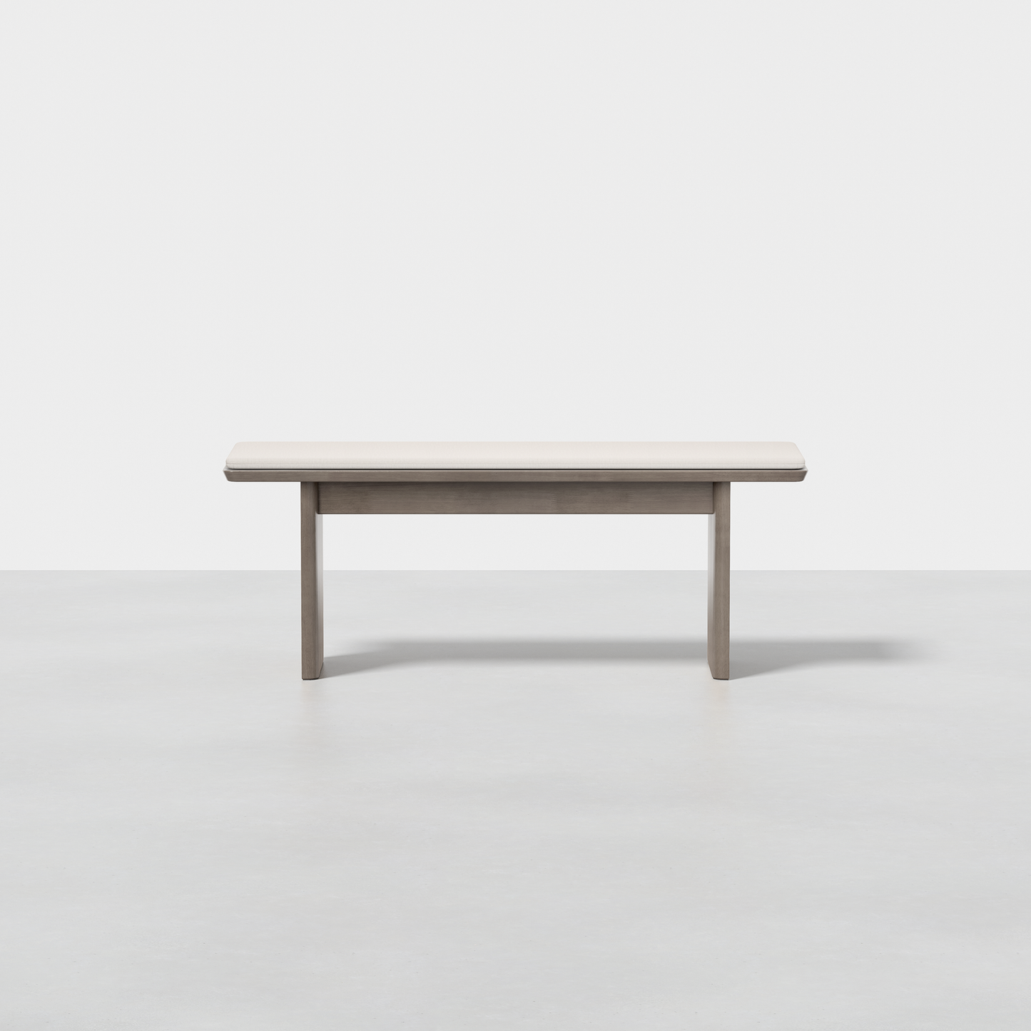 The Pillar Bench is a minimalist, rectangular wooden bench with clean lines and a light wood finish, set on a smooth light gray floor against a plain white background.