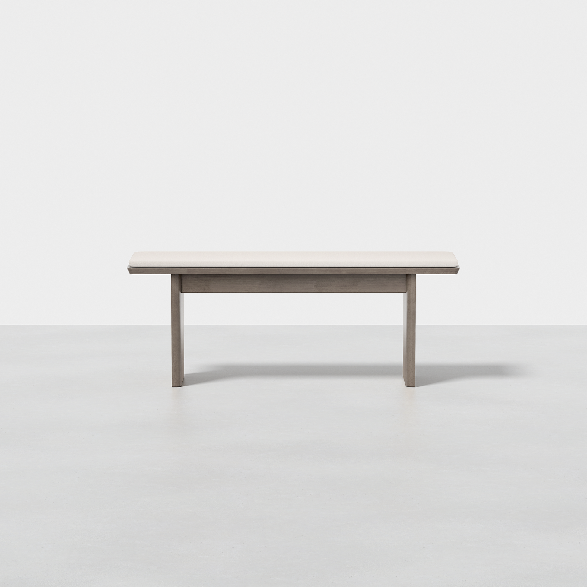 The Pillar Bench is a minimalist, rectangular wooden bench with clean lines and a light wood finish, set on a smooth light gray floor against a plain white background.