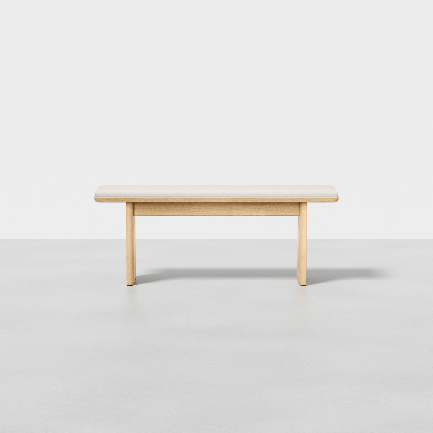 The Pillar Bench, featuring a simple modern design and light wood finish, is set against a plain white background on a smooth, light gray floor.