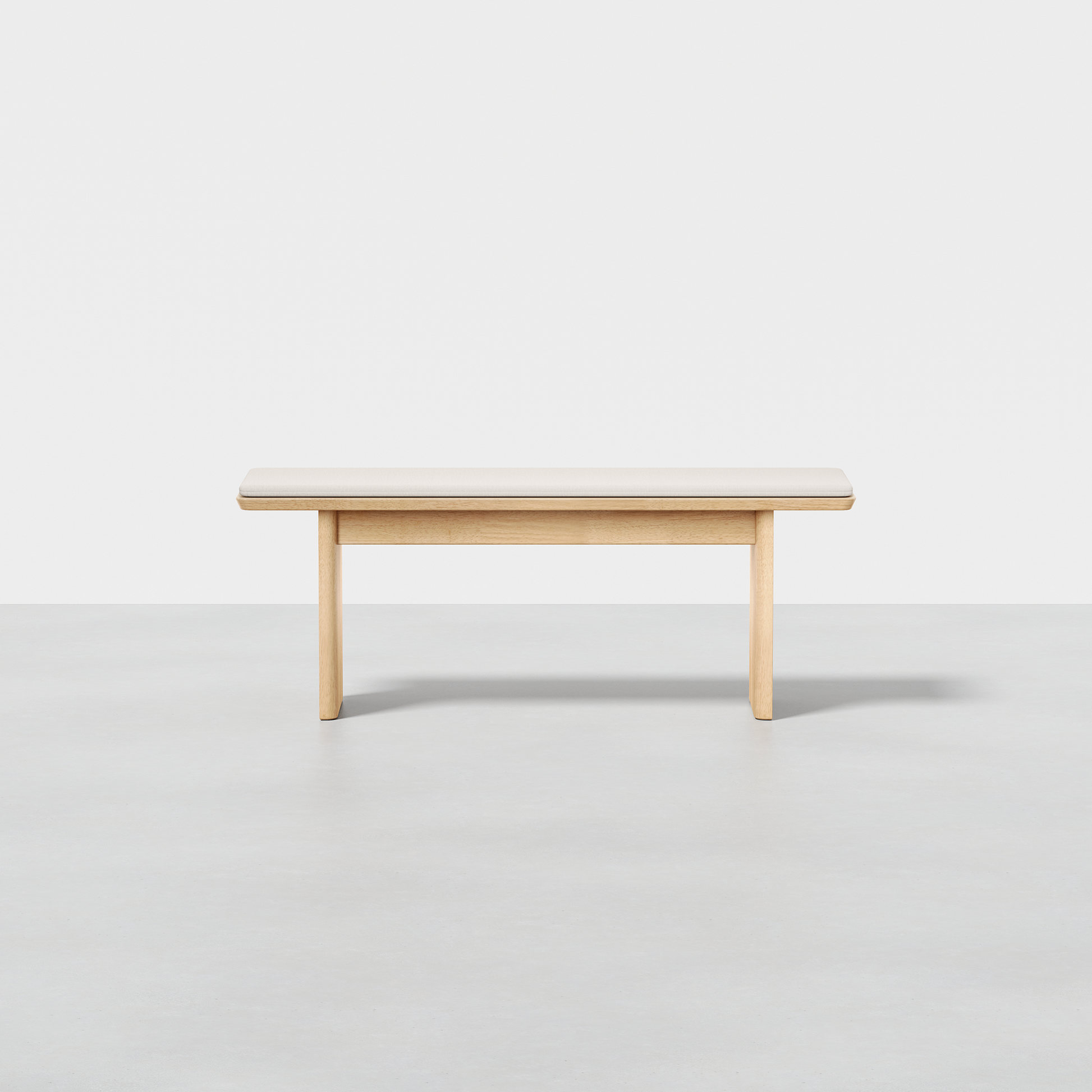 The Pillar Bench, featuring a simple modern design and light wood finish, is set against a plain white background on a smooth, light gray floor.