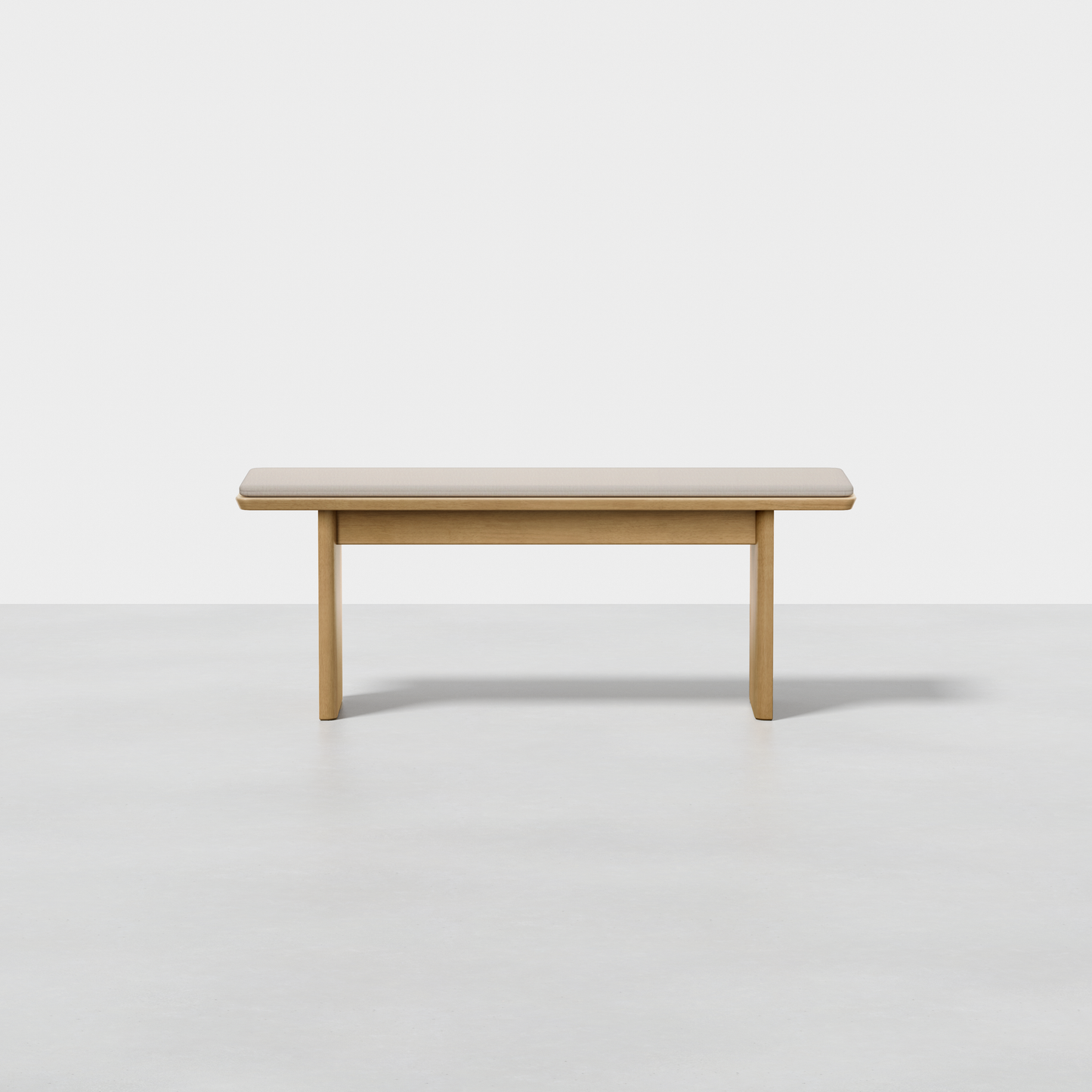 The Pillar Bench is a simple rectangular wooden bench with a smooth surface and four sturdy legs, shown on a light gray floor against a plain white background.