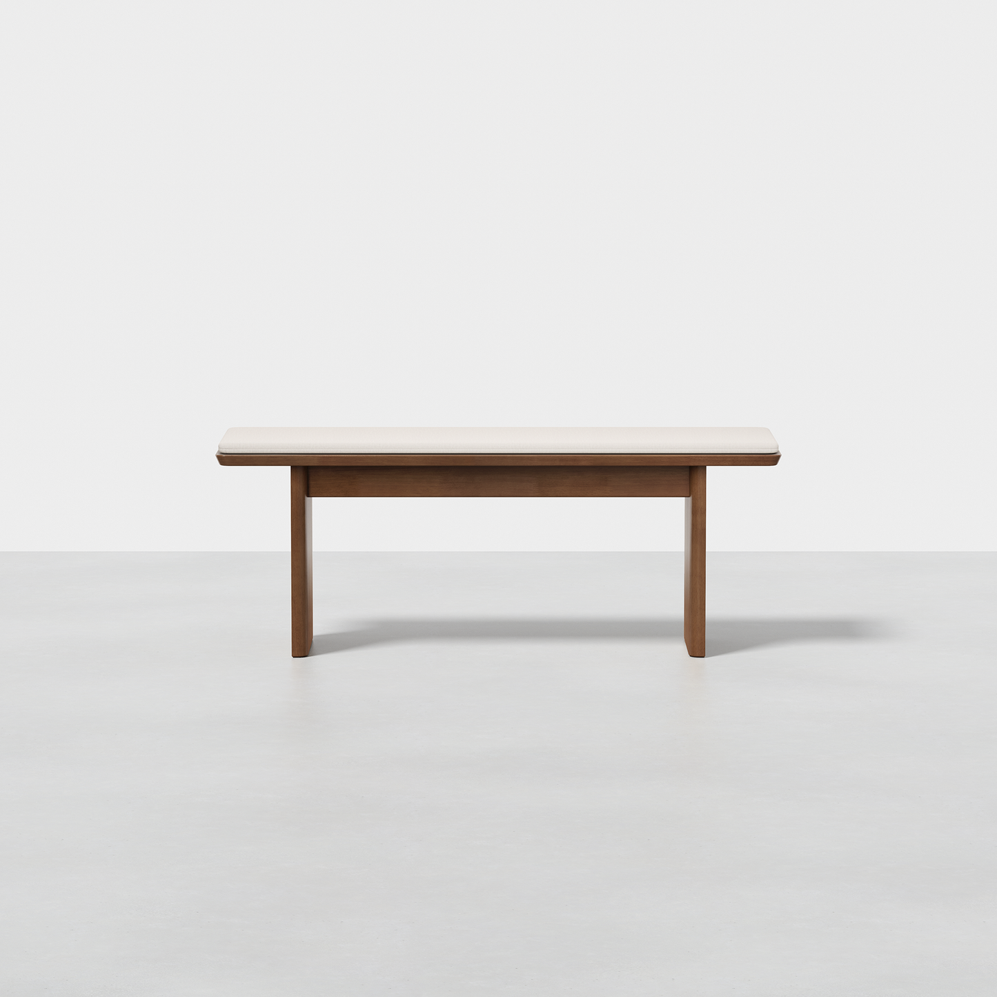 The Pillar Bench, featuring a rectangular wooden top and four sturdy legs, is displayed against a plain white background on a smooth light grey floor.