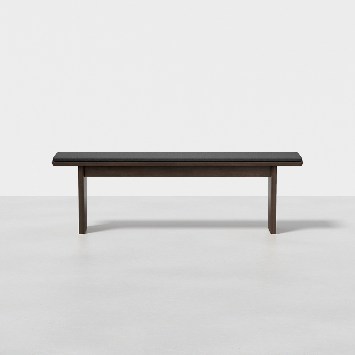 The Pillar Bench features a minimalist wooden design with straight legs and a dark cushioned seat, shown against a plain white background.