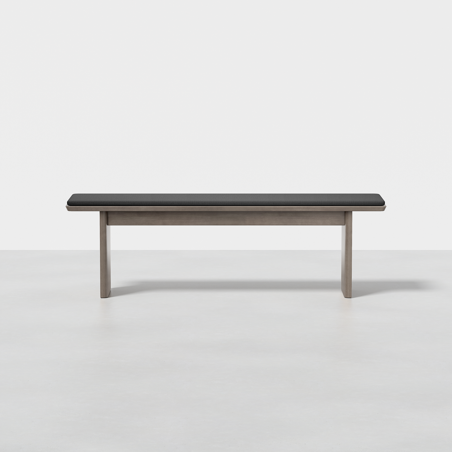 The Pillar Bench features a black cushioned seat and light wood legs, displayed against a plain white background.