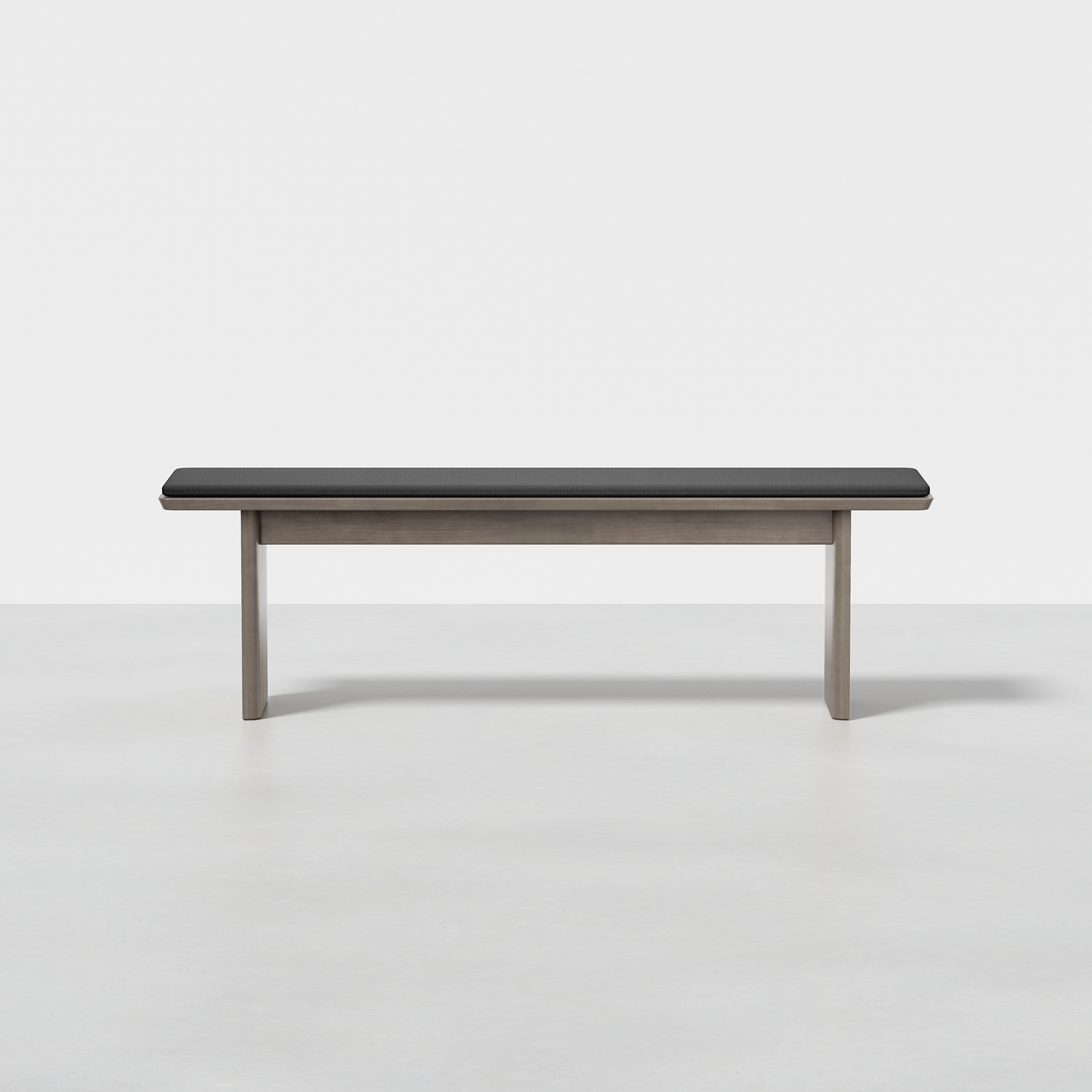 The Pillar Bench features a black cushioned seat and light wood legs, displayed against a plain white background.