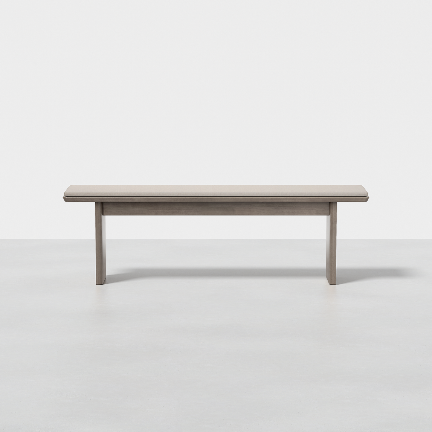 The Pillar Bench features a rectangular seat and four straight legs, finished in light gray, and is shown on a smooth, light floor against a white background.