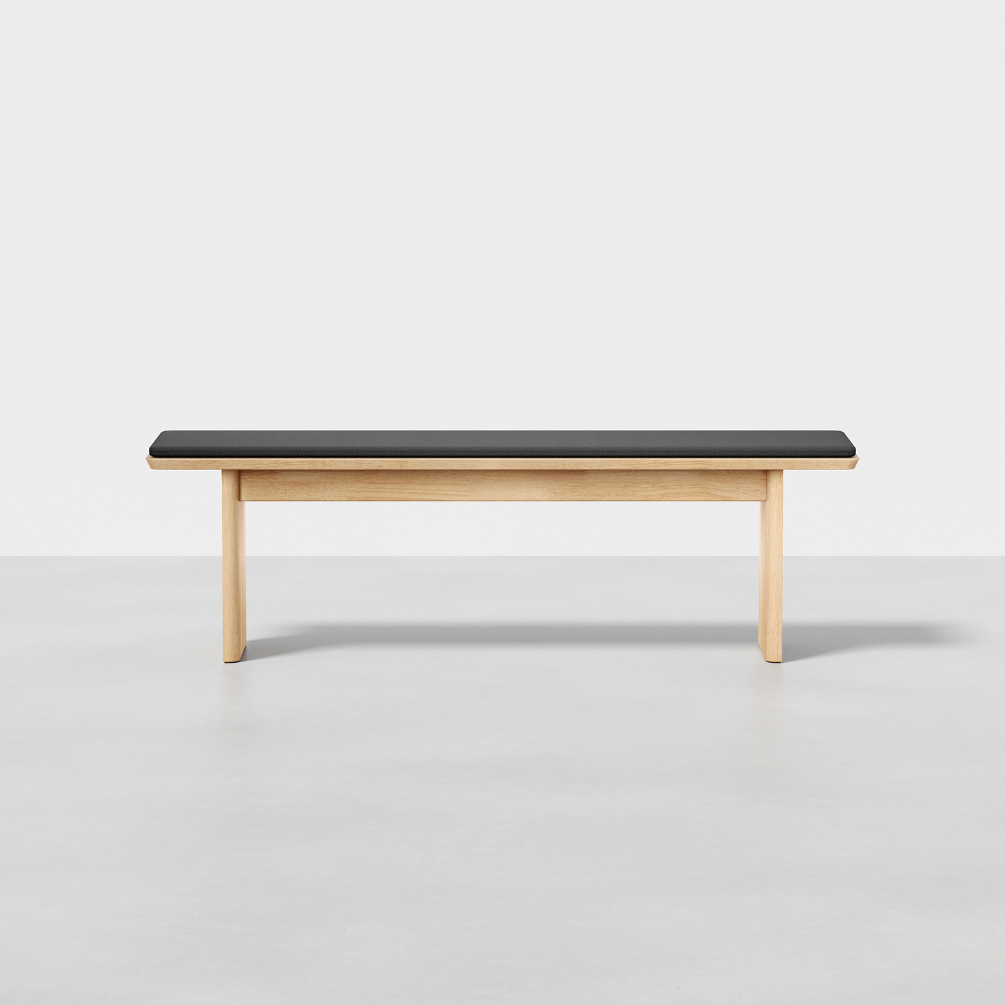 The Pillar Bench, featuring a minimalist wooden design with a black cushioned seat, is showcased against a plain white background and a light gray floor.