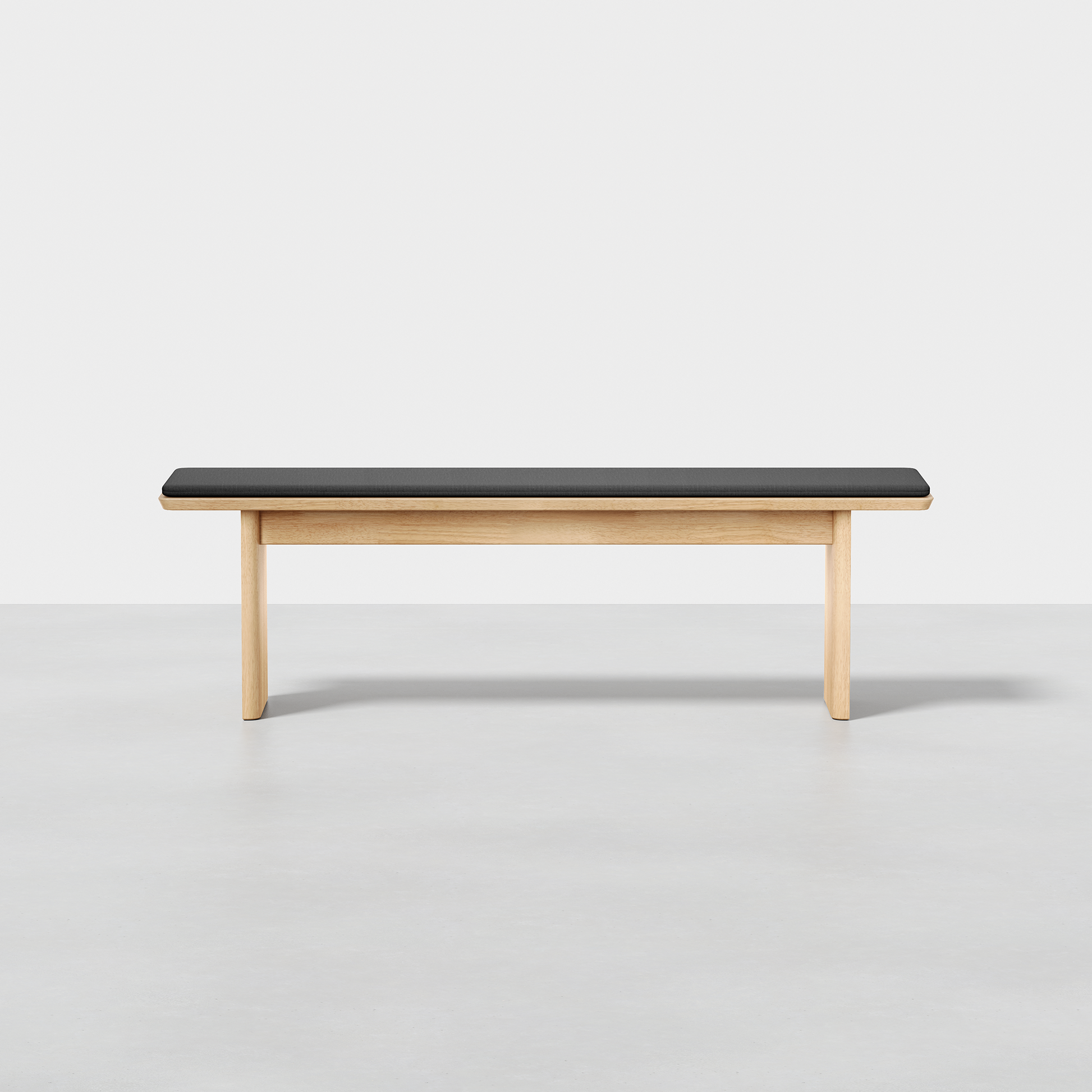The Pillar Bench, featuring a minimalist wooden design with a black cushioned seat, is showcased against a plain white background and a light gray floor.
