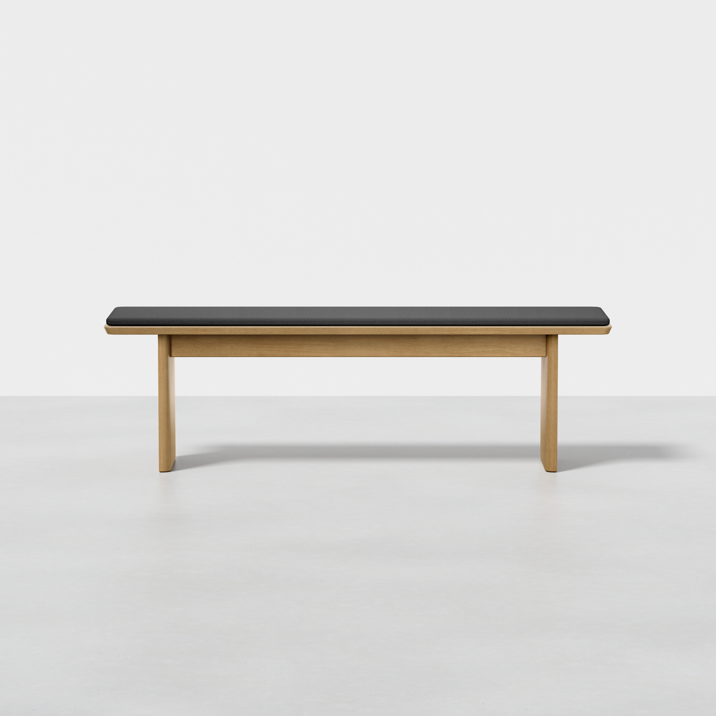 The Pillar Bench is a minimalist wooden bench featuring a rectangular black cushion on top, displayed against a plain white background.