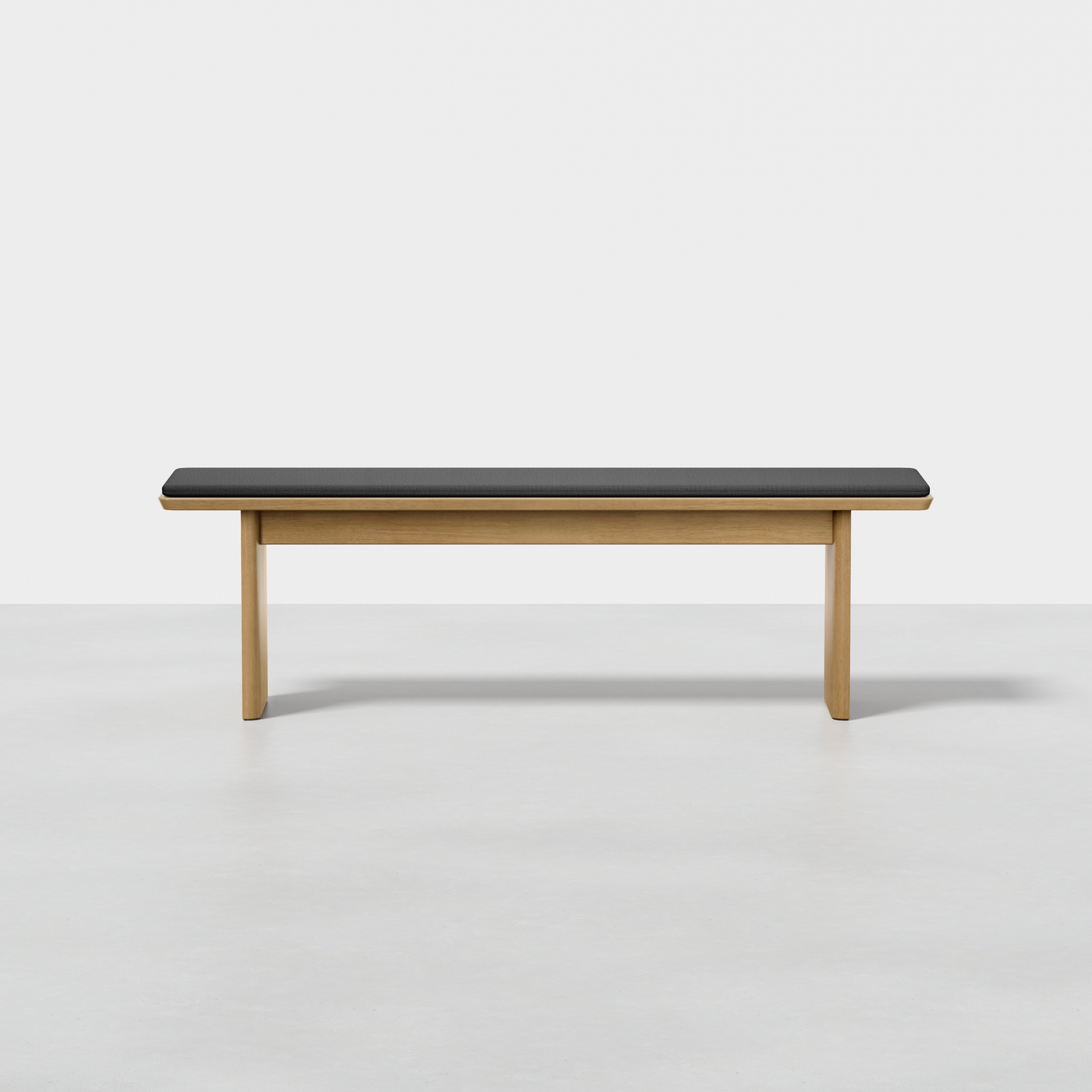 The Pillar Bench is a minimalist wooden bench featuring a rectangular black cushion on top, displayed against a plain white background.