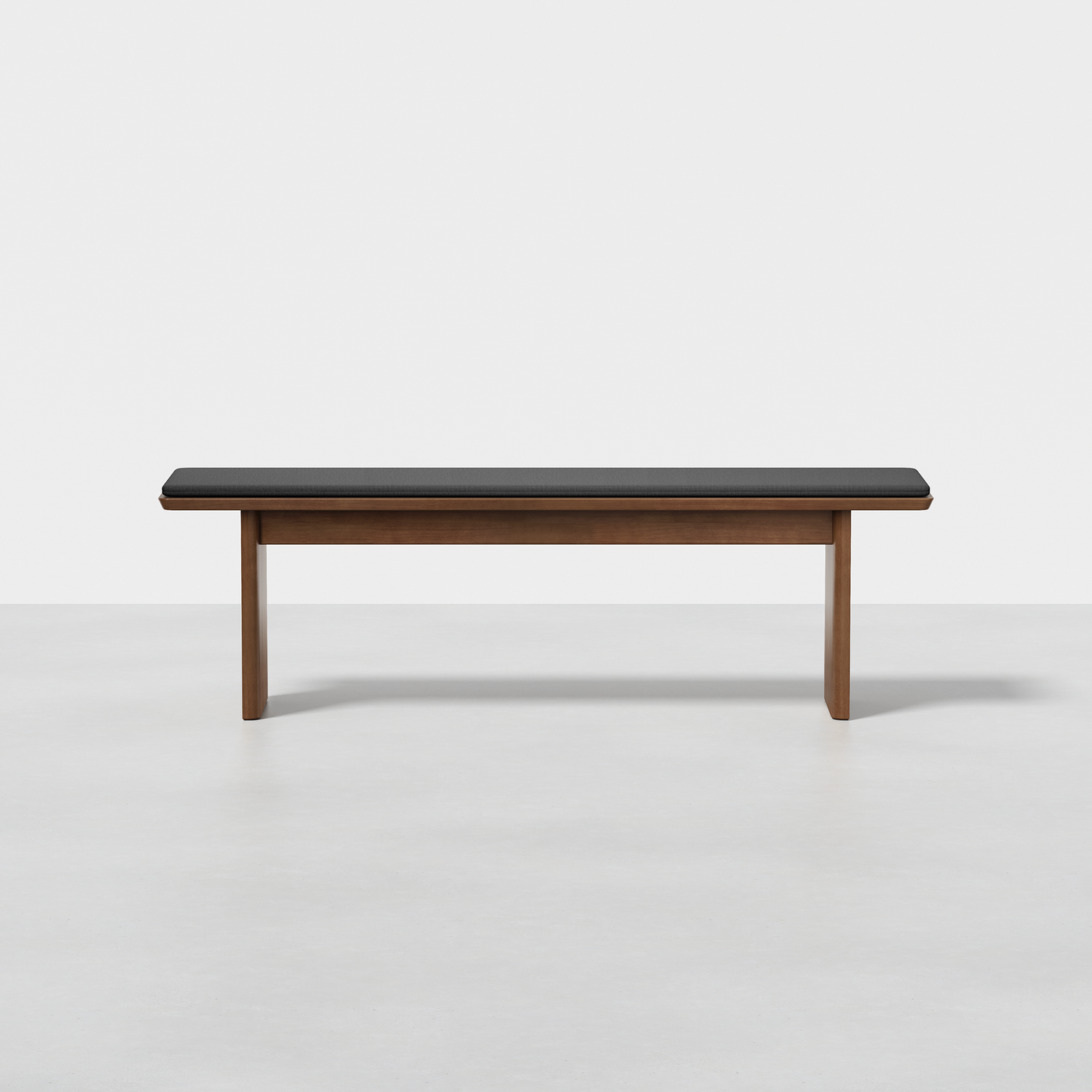The Pillar Bench is a modern wooden bench with a dark cushioned seat, featuring clean lines and a minimalist design, set against a plain white background.
