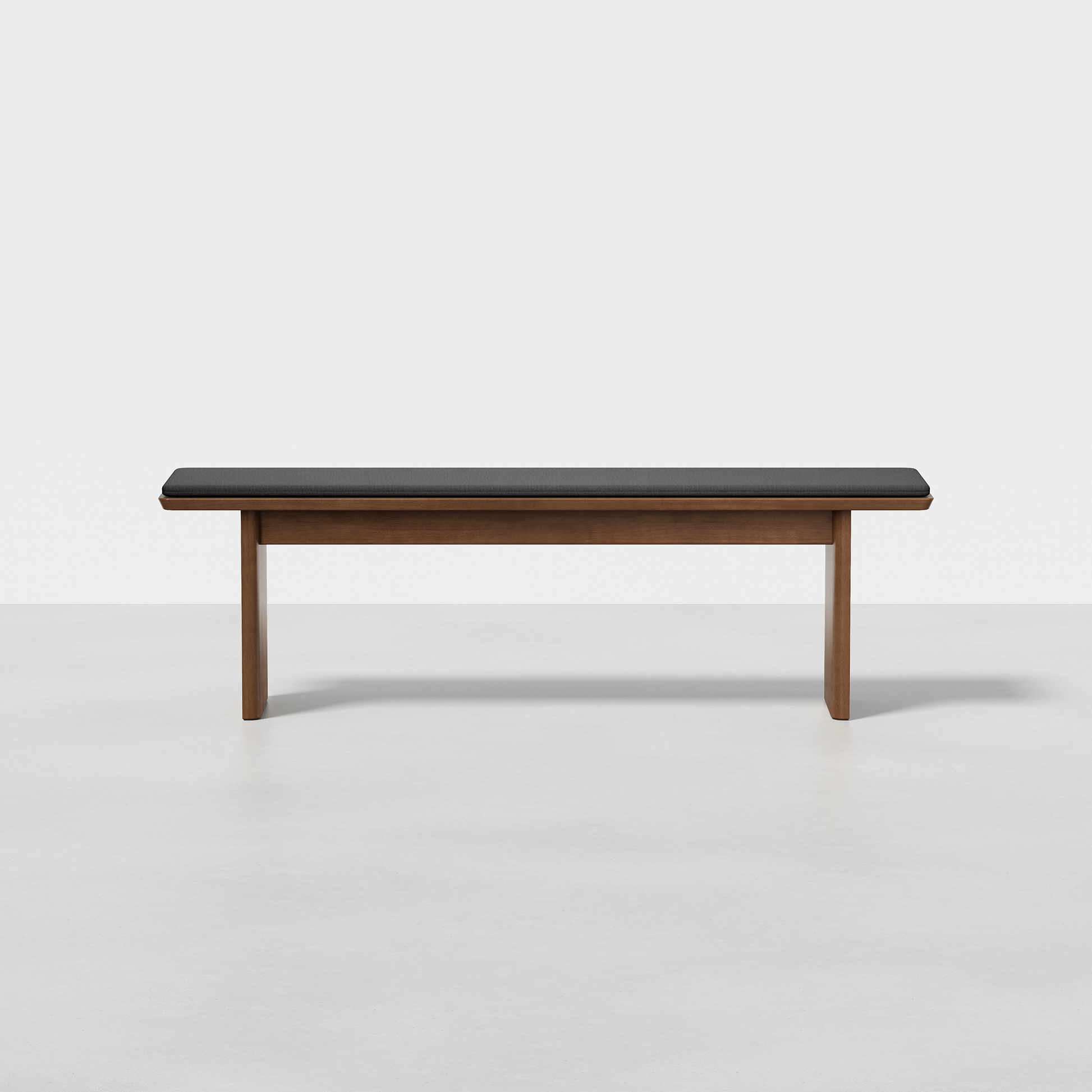 The Pillar Bench is a modern wooden bench with a dark cushioned seat, featuring clean lines and a minimalist design, set against a plain white background.